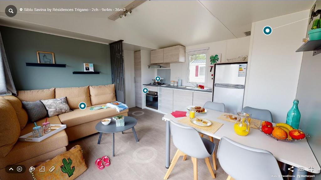 eine Küche und ein Wohnzimmer mit einem Tisch und einem Sofa in der Unterkunft Mobil Home Le Rimbaud - 4/6 pers - 2 ch - 2 sdb in Saint-Jean-de-Monts