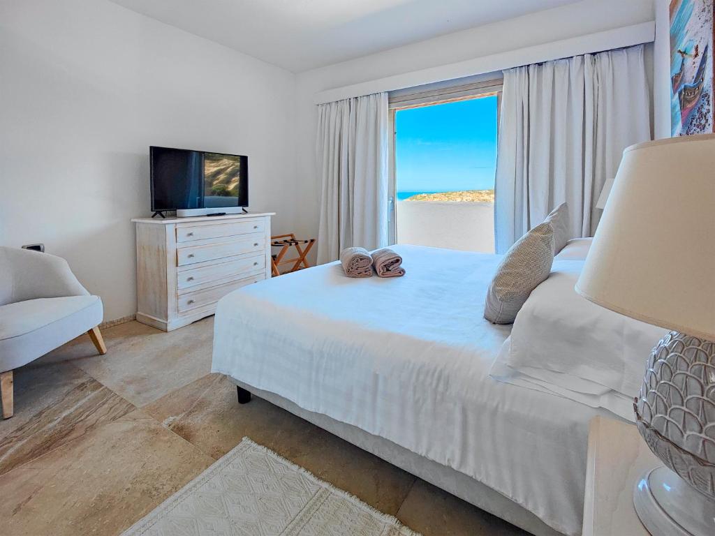 Schlafzimmer mit einem Bett, einem TV und einem Fenster in der Unterkunft Residence Balocco Porto Cervo in Porto Cervo