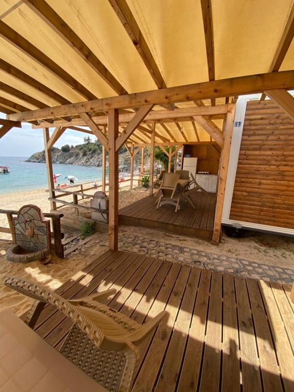una terraza de madera con sillas en la playa en Camping Anamour, en Toroni