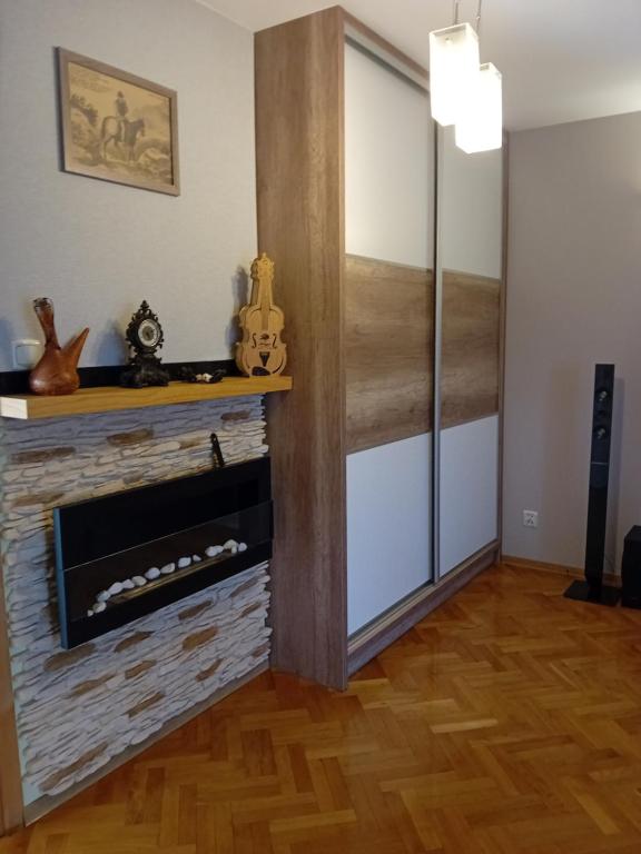 a living room with a fireplace and a refrigerator at Orkana44F in Mszana Dolna