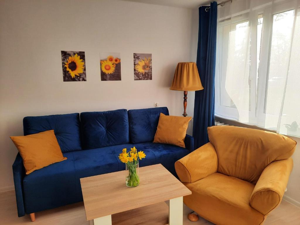 sala de estar con sofá azul, silla y mesa en Apartament Bałtycka Sardynka en Ustka