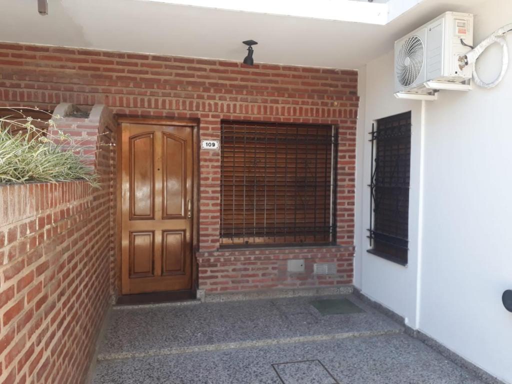 un muro di mattoni con porta in legno e finestra di FRIDA APARTMENT remis gratis a Ezeiza a Ezeiza