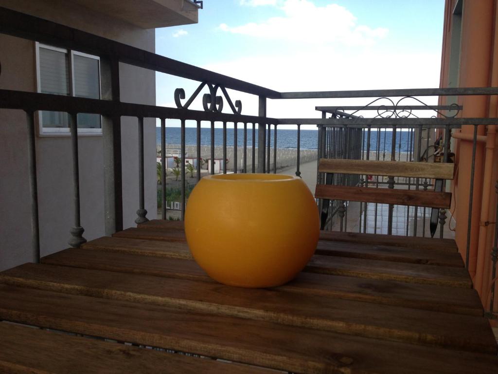 un gran jarrón naranja sentado en un balcón de madera en Beach mini appartamento, en Margherita di Savoia