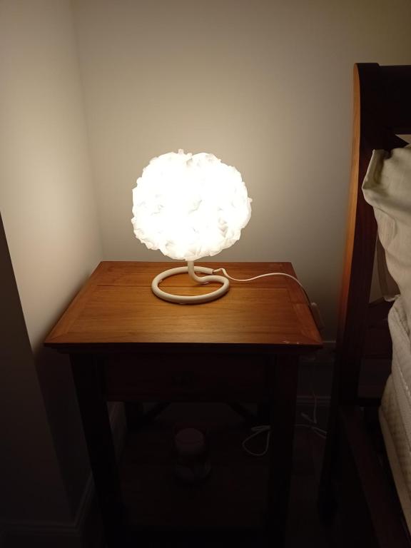 a white lamp on a wooden table next to a bed at Ama&#39;s Sweet home in Saint-Hubert
