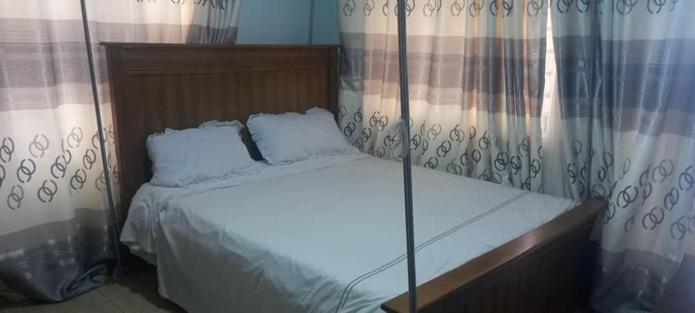 uma cama com duas almofadas num quarto em Nelly Apartments em Mbale