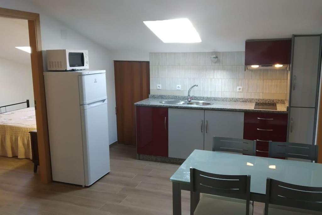 a kitchen with a refrigerator and a table with chairs at Gala T1+ in Figueira da Foz