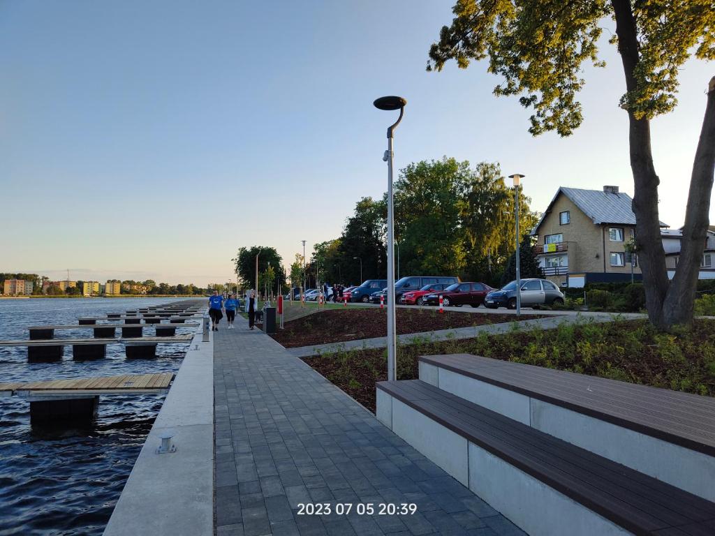 a sidewalk next to the water with benches and a street light at Ośrodek Wczasowy Daga in Dziwnów