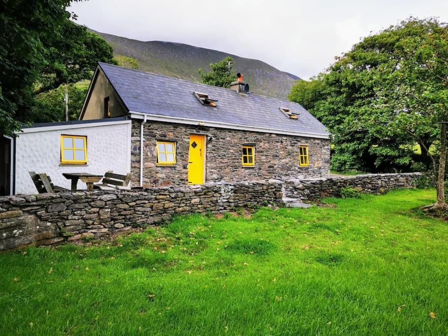 uma casa de pedra com um homem sentado em cima dela em Cottage Skelligs Coast, Ring of Kerry em Cahersiveen