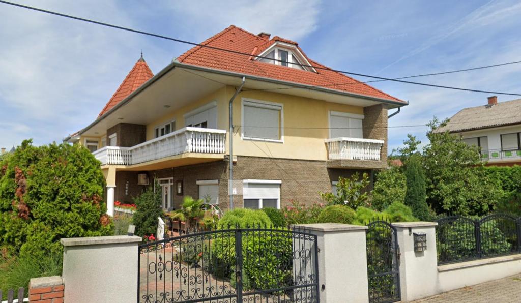 une maison avec une clôture en fer devant elle dans l'établissement Sárga-Kék ház, à Vonyarcvashegy