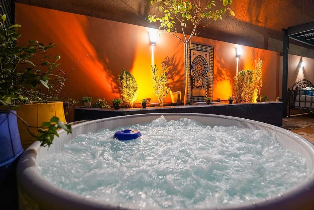 een bad gevuld met water in een kamer met planten bij DarSublime au cœur de Marrakech Jacuzzi privé in Marrakesh