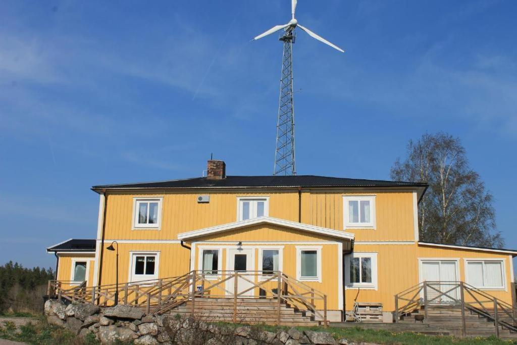 ein großes gelbes Haus mit einer Windmühle darüber in der Unterkunft Skräpplinge gård in Mörlunda