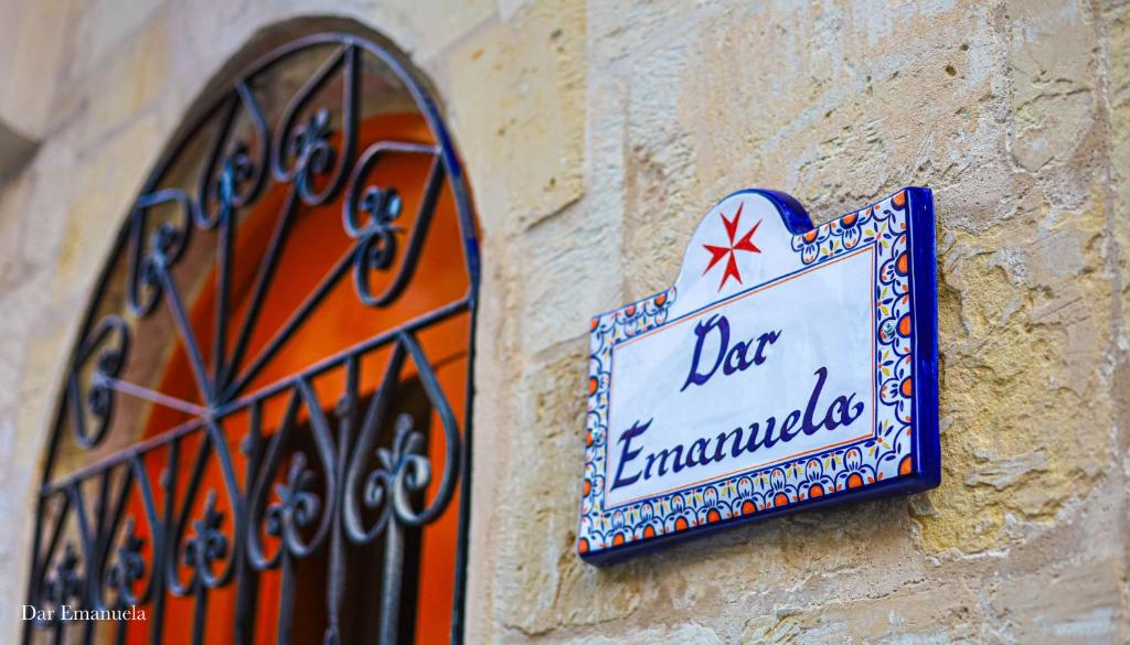 un panneau sur le côté d'un bâtiment dans l'établissement 150 years old Maltese Townhouse: Dar Emanuela, à Cospicua