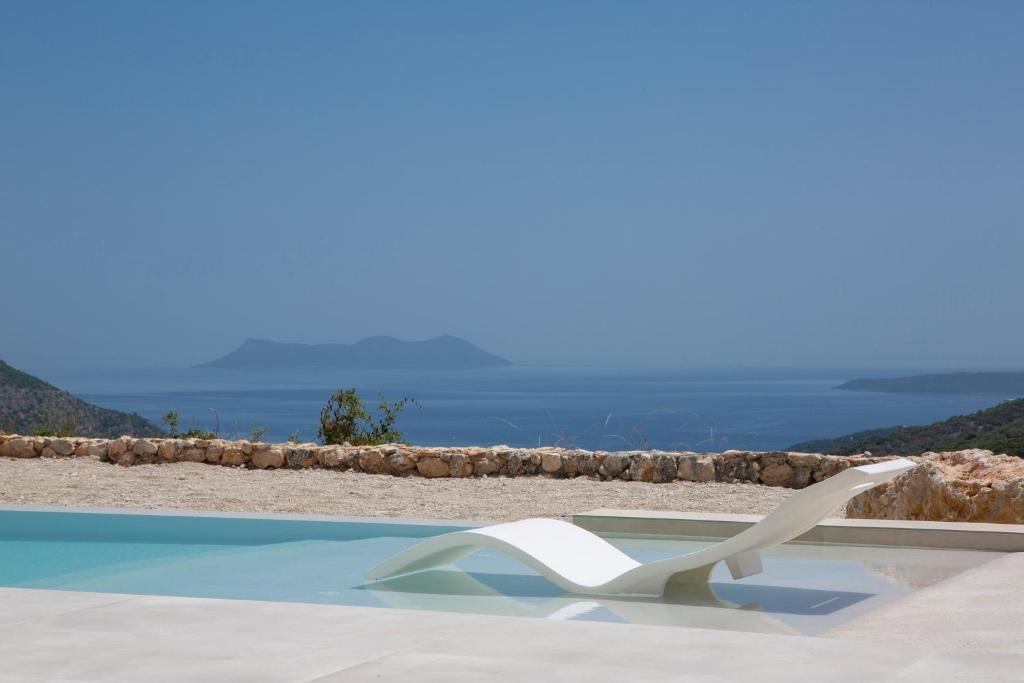 una sedia bianca seduta accanto alla piscina di Armante Supreme Villas - Villa Ilianna a Fternón