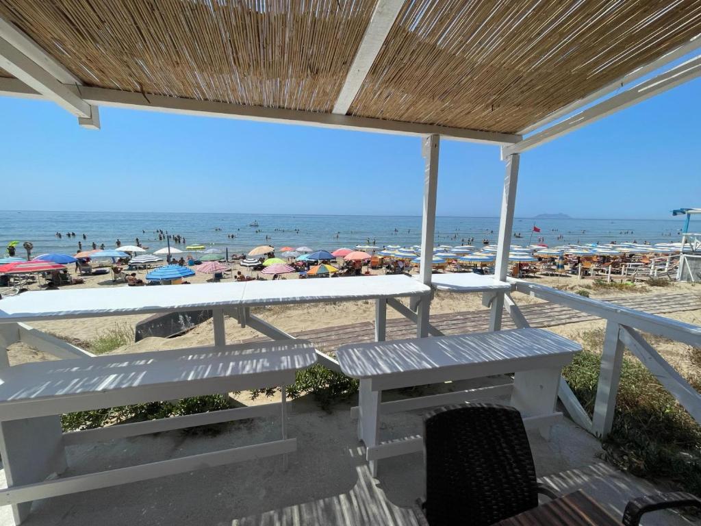 een uitzicht op een strand met een bank en parasols bij SPERLONGA VILLETTA SUL MARE CON ACCESSO ALLE SPIAGGIA POSIZIONE ESCLUSIVA in Sperlonga