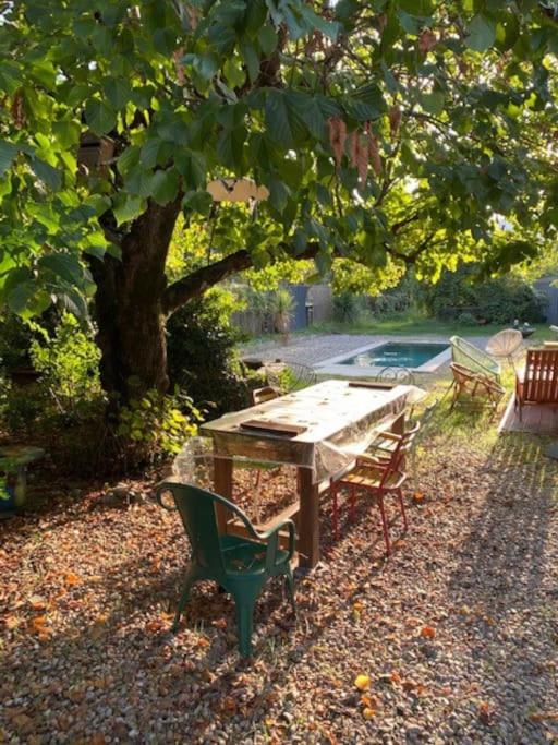 une table et des chaises en bois sous un arbre dans l'établissement Mazet avec jardin, à Saint-Bauzille-de-Putois