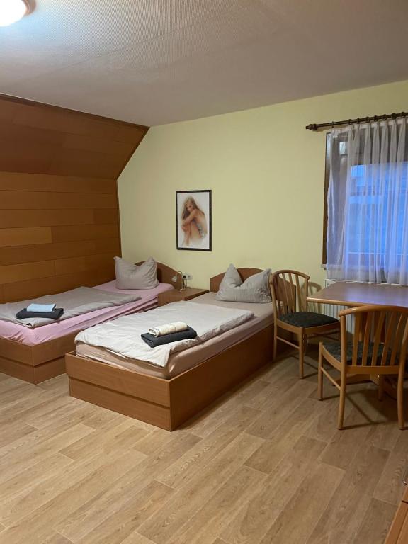 2 camas en una habitación con mesa y sillas en Pension Sandsteinhöhle, en Walldorf