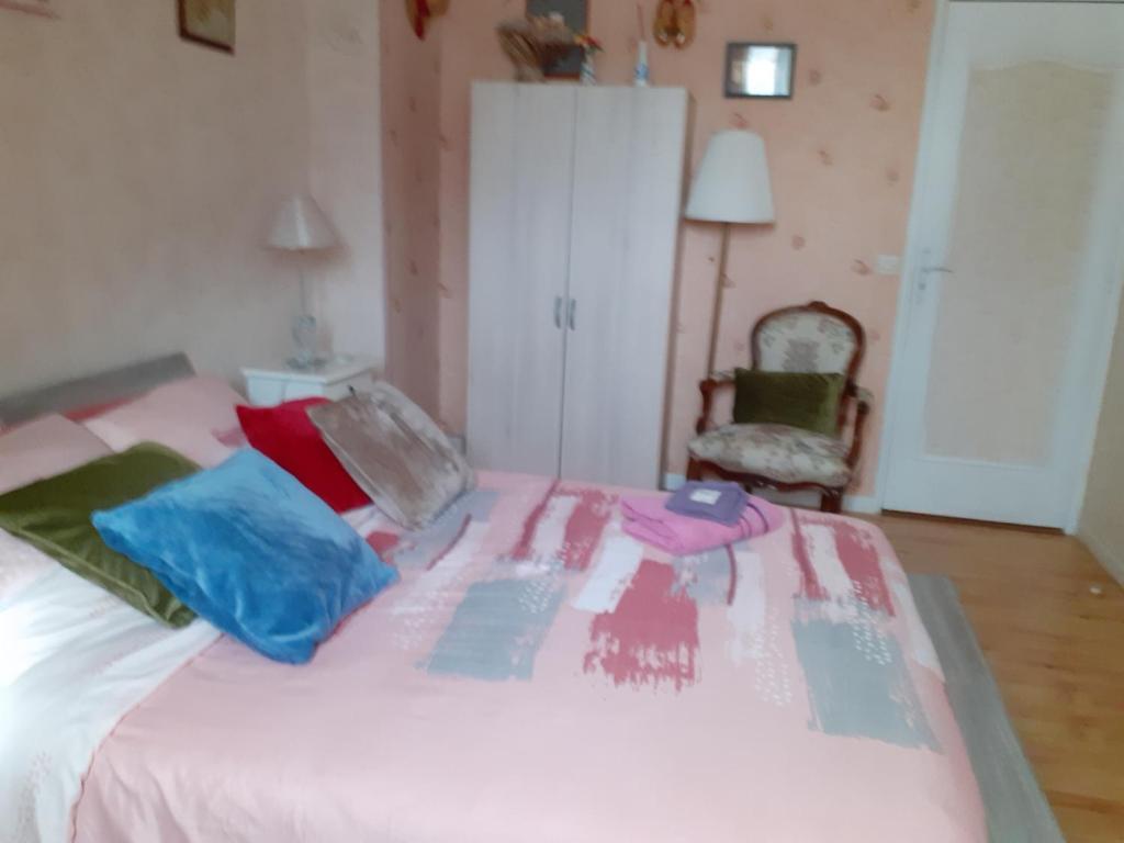 ein Schlafzimmer mit einem weißen Bett und bunten Kissen in der Unterkunft chambre d'hôte "Chambre dans une maison pleine de vie" in Saint-Rémy-lès-Chevreuse
