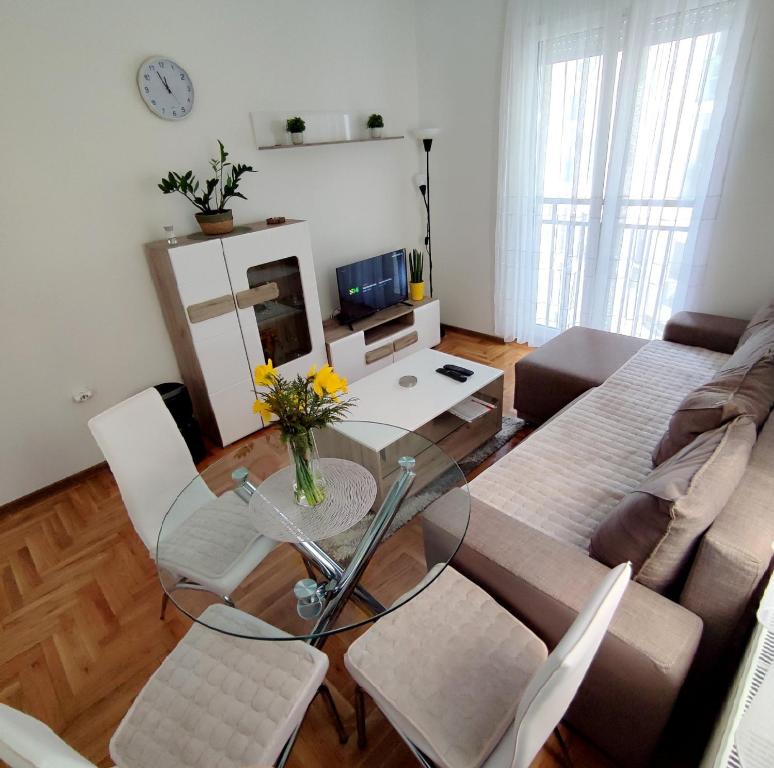ein Wohnzimmer mit einem Glastisch und einem Sofa in der Unterkunft Stan na dan Sanja in Novi Sad