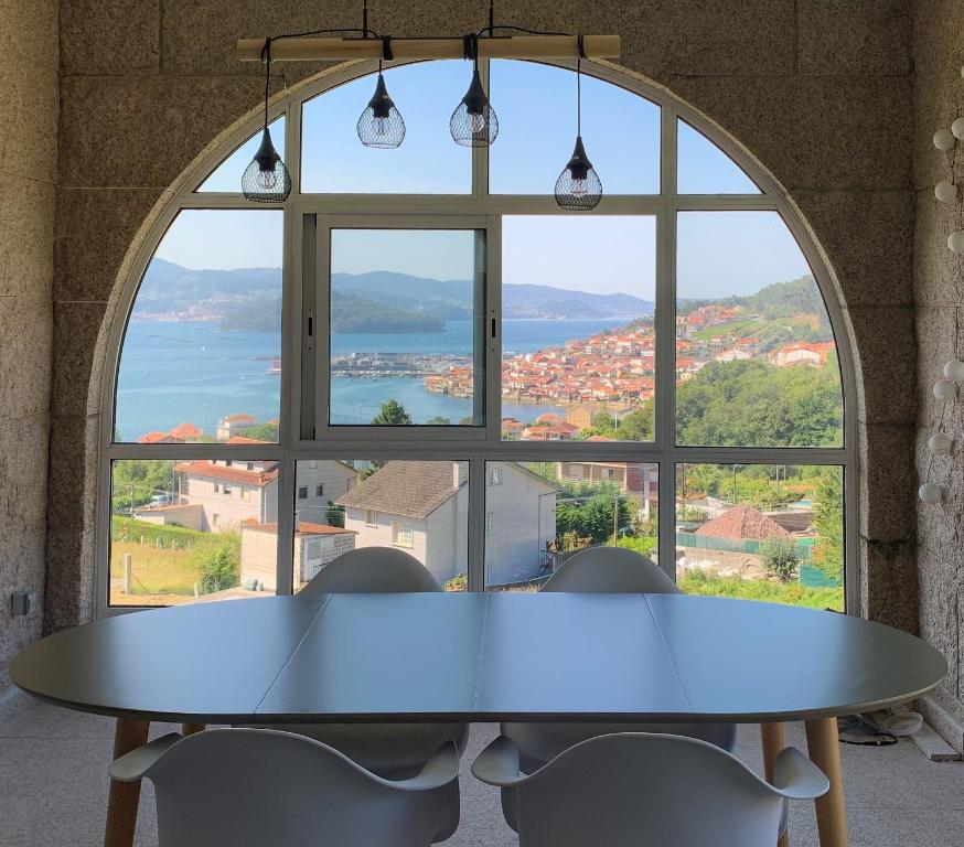 un tavolo con sedie di fronte a una grande finestra di Combarro Vista a Combarro