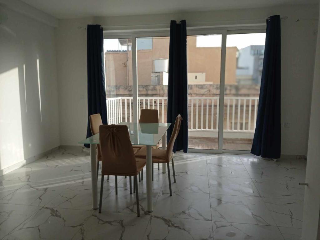 a dining room with a table and chairs and a balcony at Poppy Court in Marsaskala