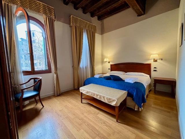 a bedroom with a bed and a chair and a window at Locanda del Ghetto in Venice