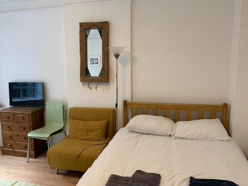 a bedroom with a bed and a chair and a mirror at Covent Garden 2 Bed Apartment in London