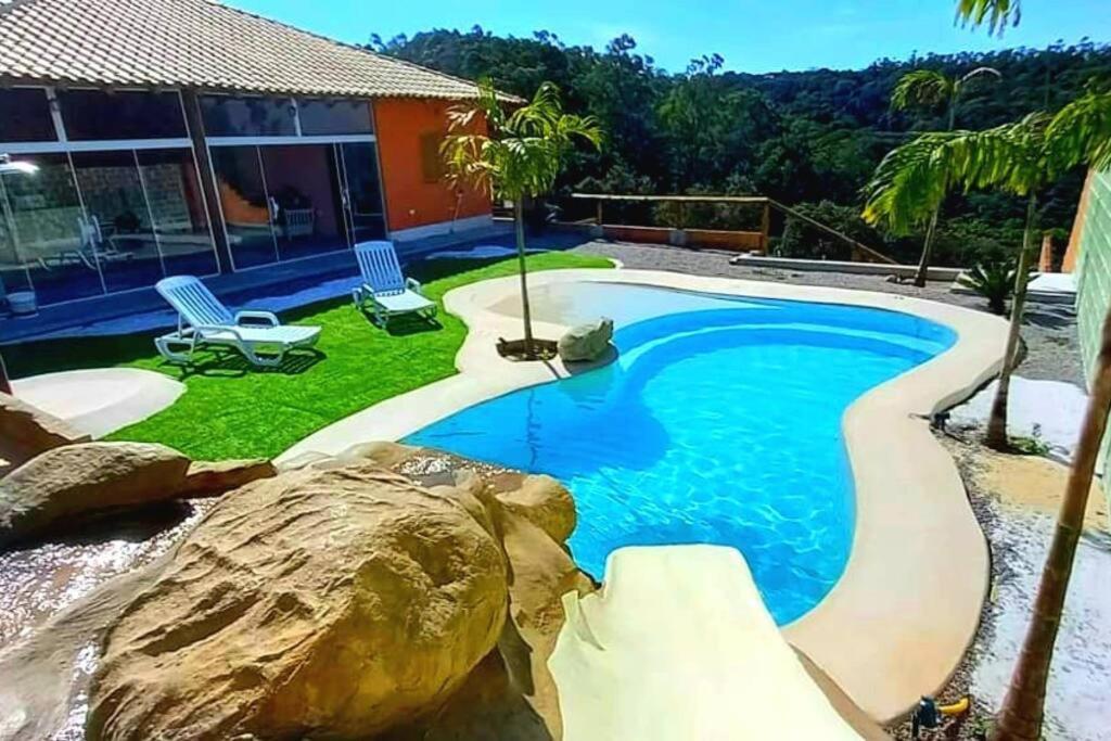 a swimming pool with a rock in a yard at Rancho Saramago in Jundiaí