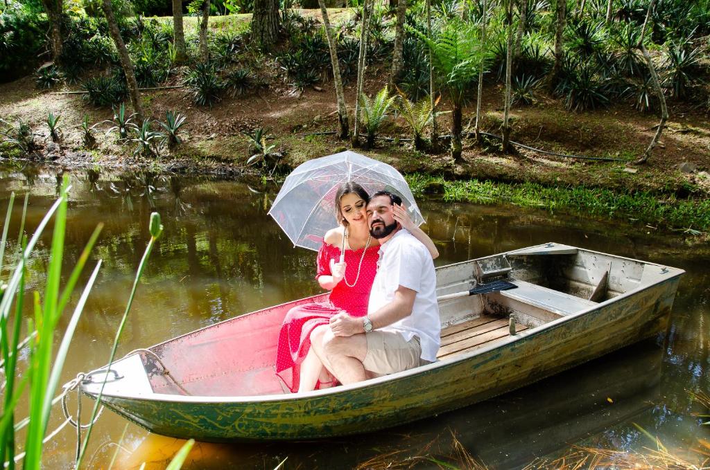 um homem e uma mulher sentados num barco com um guarda-chuva em Pousada Santuário Acalanto em São Roque