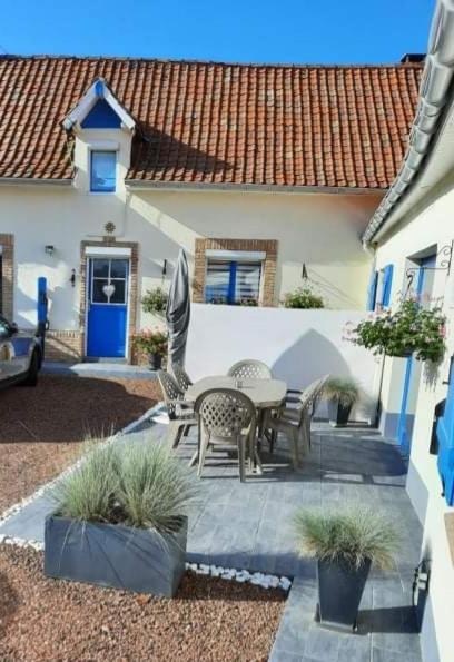un patio avec une table et des chaises devant une maison dans l'établissement Gîte ZEN LA CAMPAGNE A LA MER, à Bréxent-Énocq