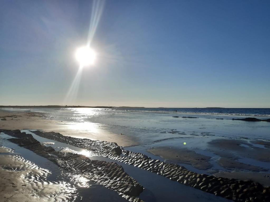 a sun is shining on a beach with water at Atlantic lodge in Ahnagh Cross