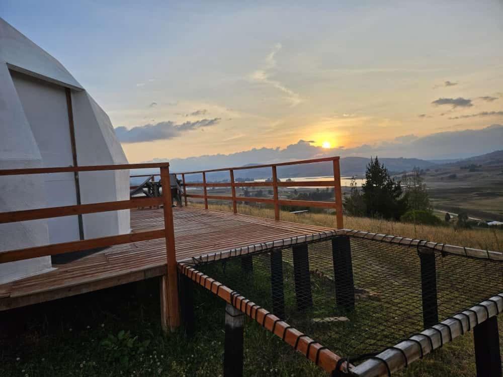 a wooden deck with a sunset in the background at El Rodeo Glamping in Toca