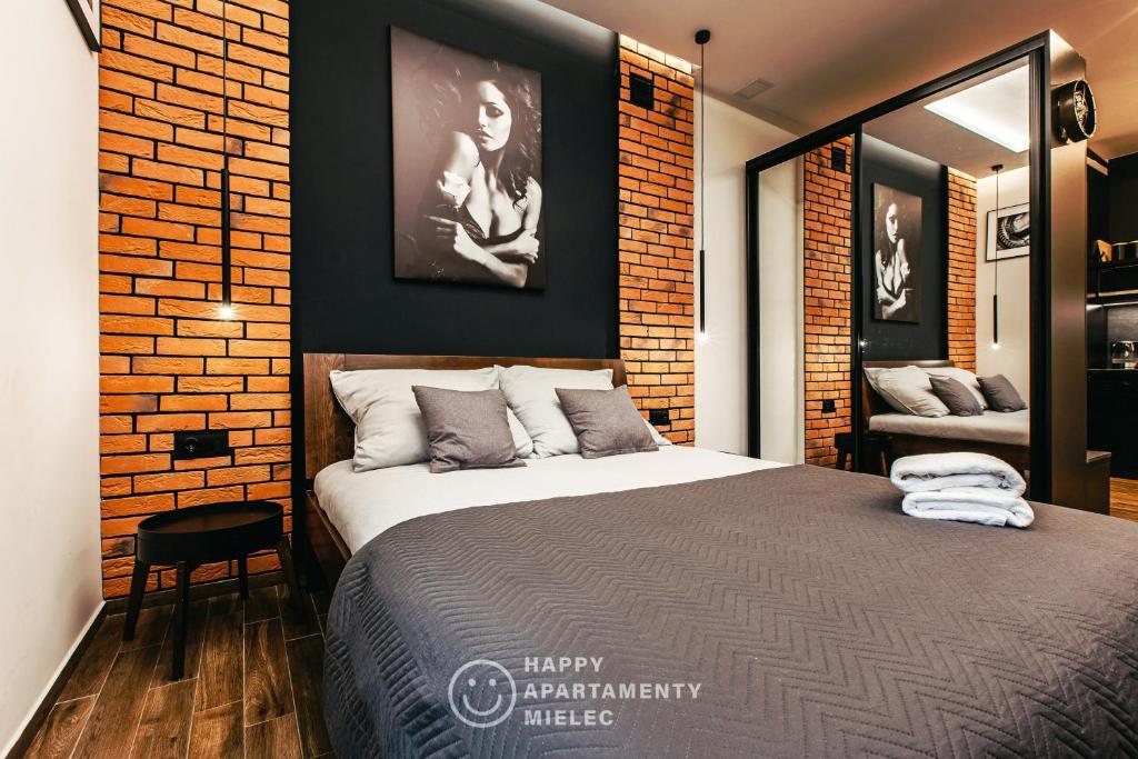 a bedroom with a large bed and a brick wall at Happy Nest - Apartamenty Happy Mielec in Mielec