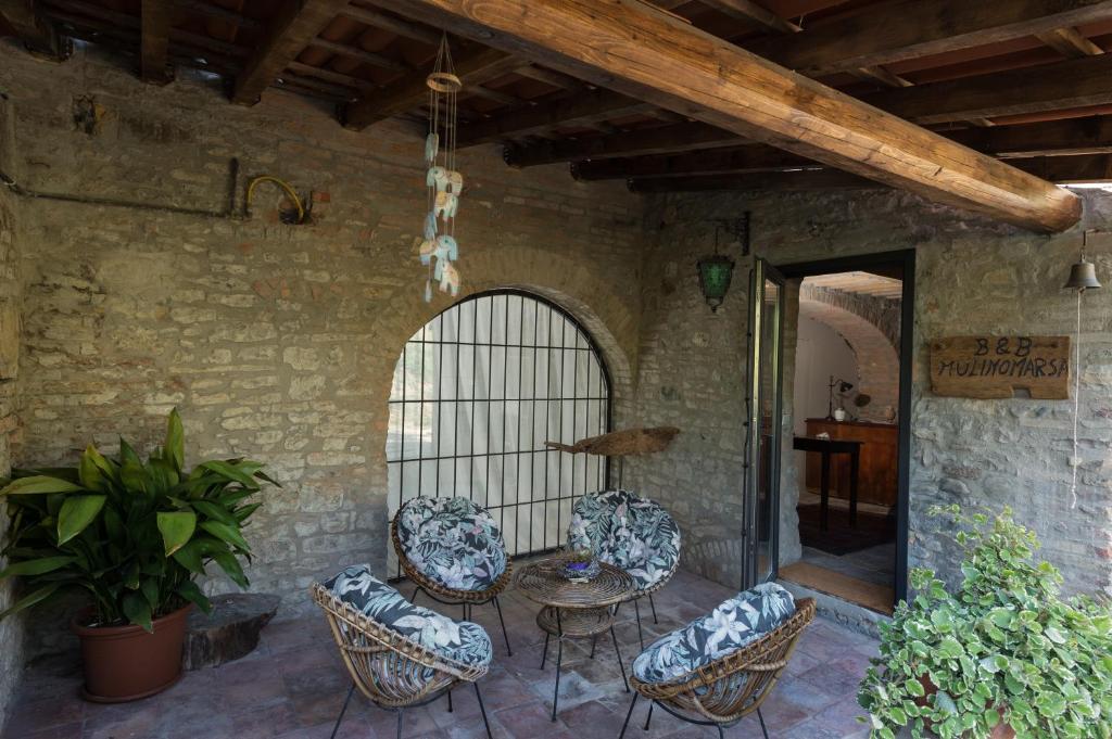un patio con sillas y una mesa en un edificio en B&B Mulino Marsa, en CastellʼArquato