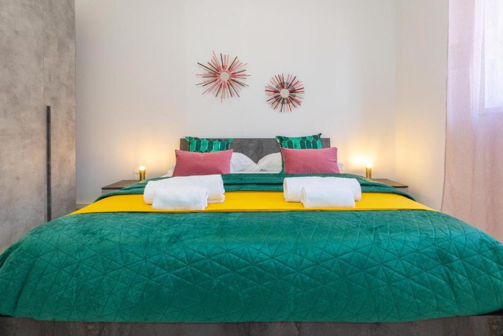 a large green bed with pink and green sheets at Medea home in Catania