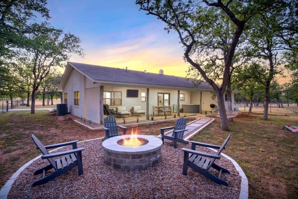 a group of benches sitting around a fire pit in front of a house at Baron's Bungalow with hot tub & pet friendly in Fredericksburg