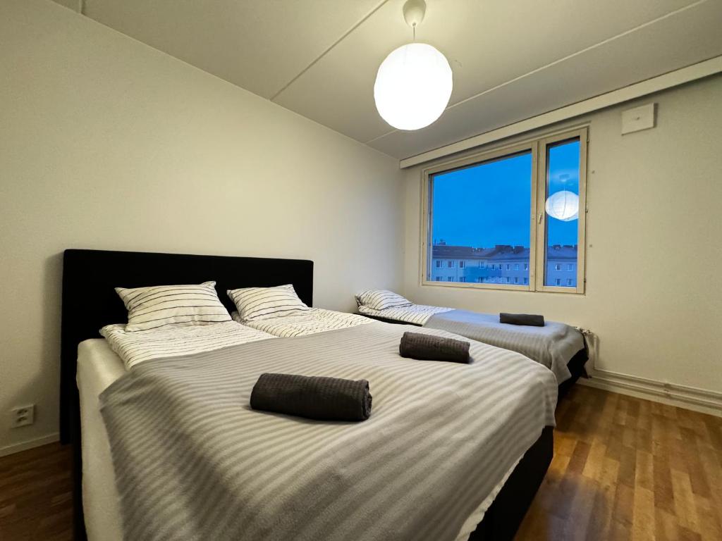 two beds in a room with a large window at DownTown Rooms And Sauna in Helsinki