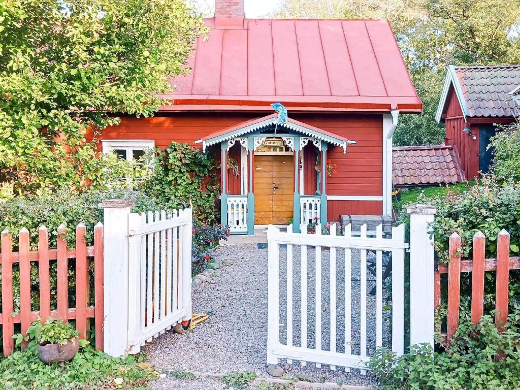 uma casa vermelha com uma cerca branca e um portão em Holiday home Mantorp em Mantorp