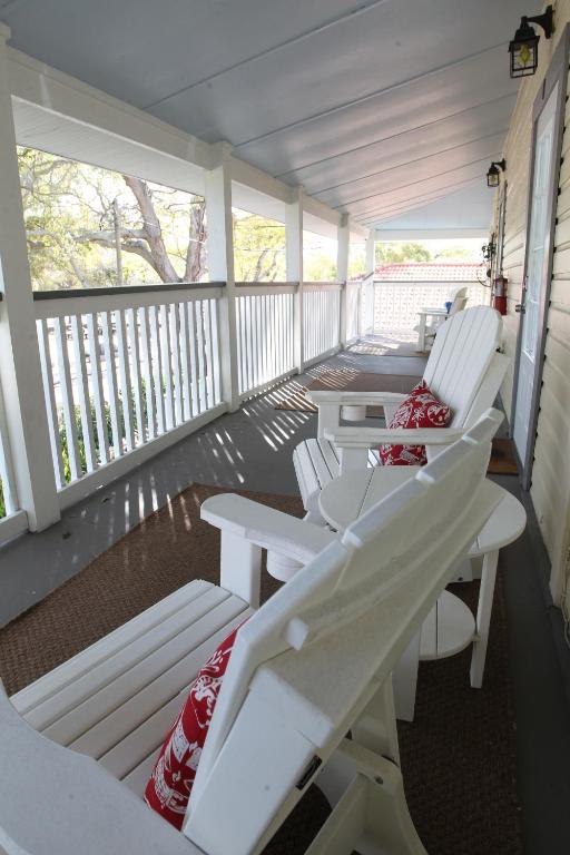 een rij witte stoelen op een veranda bij 2 Bedroom Apt Overlooking Dunedin Town Square NO PETS in Dunedin