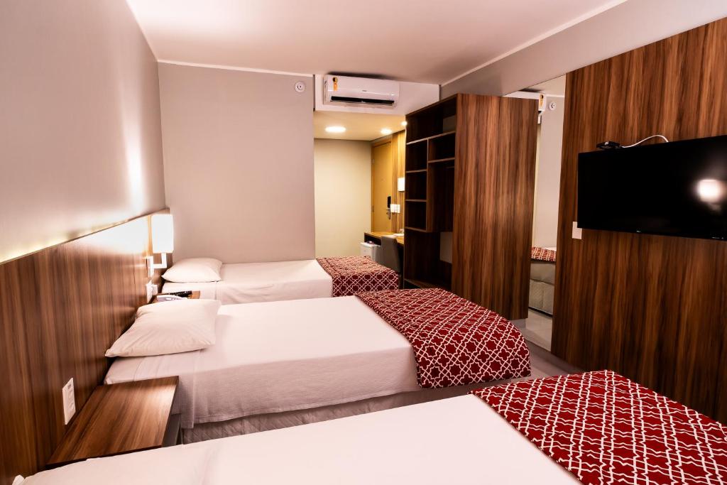 a hotel room with two beds and a flat screen tv at Stop Way Hotel Fortaleza in Fortaleza