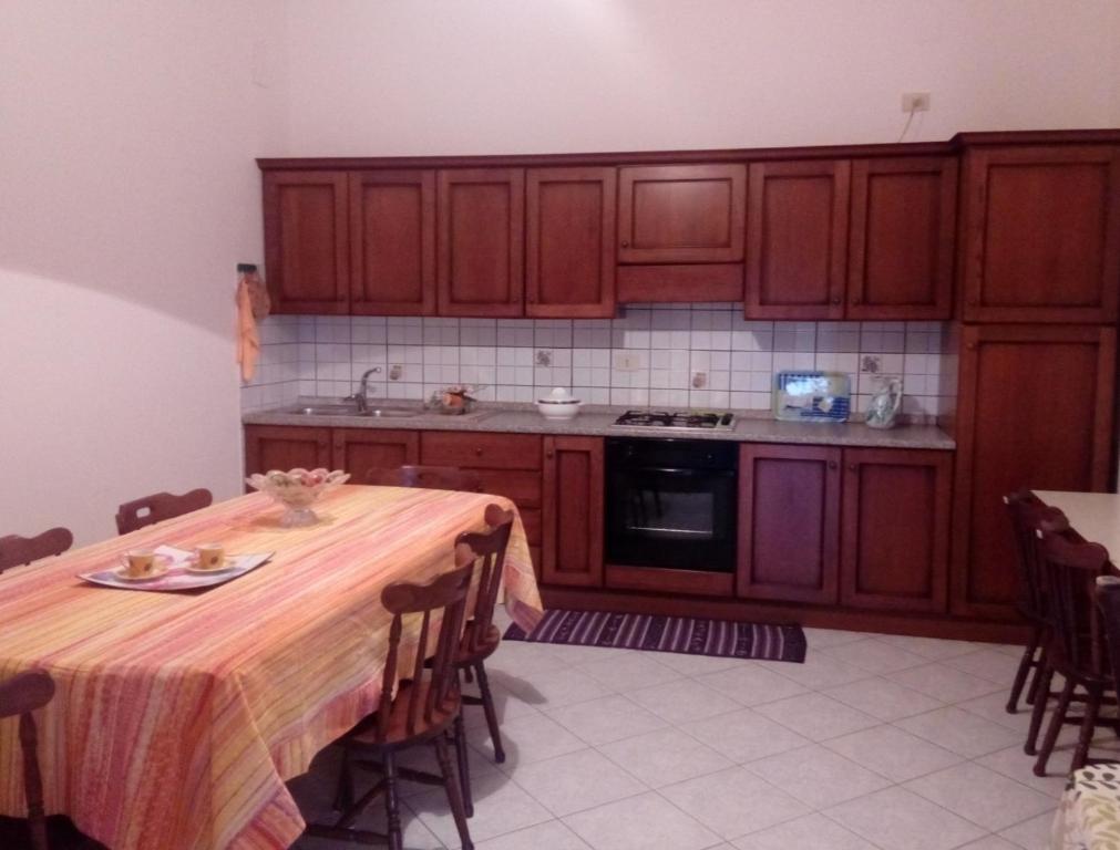 cocina con armarios de madera y mesa con mantel en Su Giardinu, en Girasole