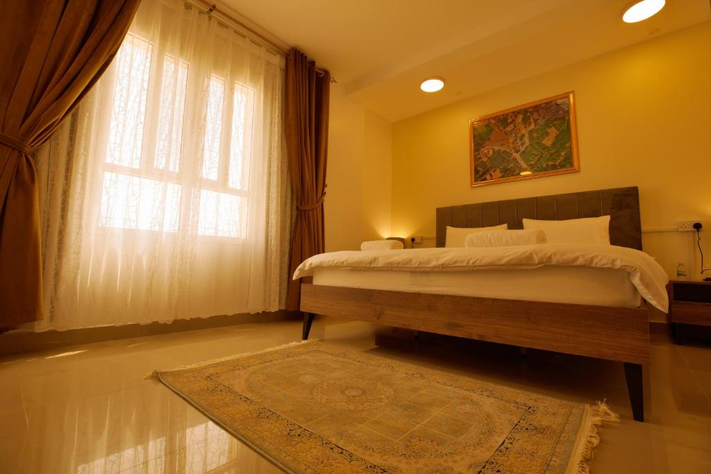 a bedroom with a bed with a window and a rug at Alhamra Horizons in Al Ḩamrāʼ