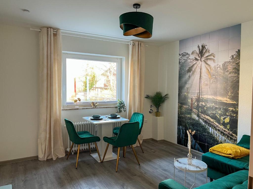ein Wohnzimmer mit einem Tisch und grünen Stühlen in der Unterkunft Top Lage - Bali-Appartment Hamburg in Hamburg