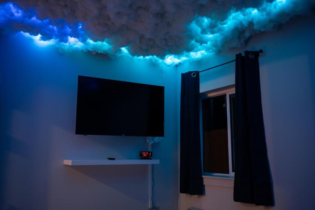 un televisor en una pared azul con nubes en el techo en Nimbus Cloud King Suite W/ Great Access to City en Filadelfia
