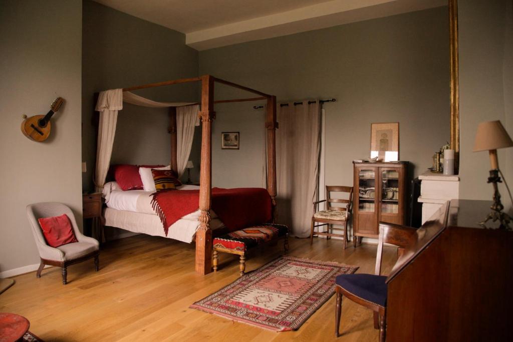 Chateau de Maumont في Magnac-sur-Touvre: غرفة نوم مع سرير مظلة وأريكة