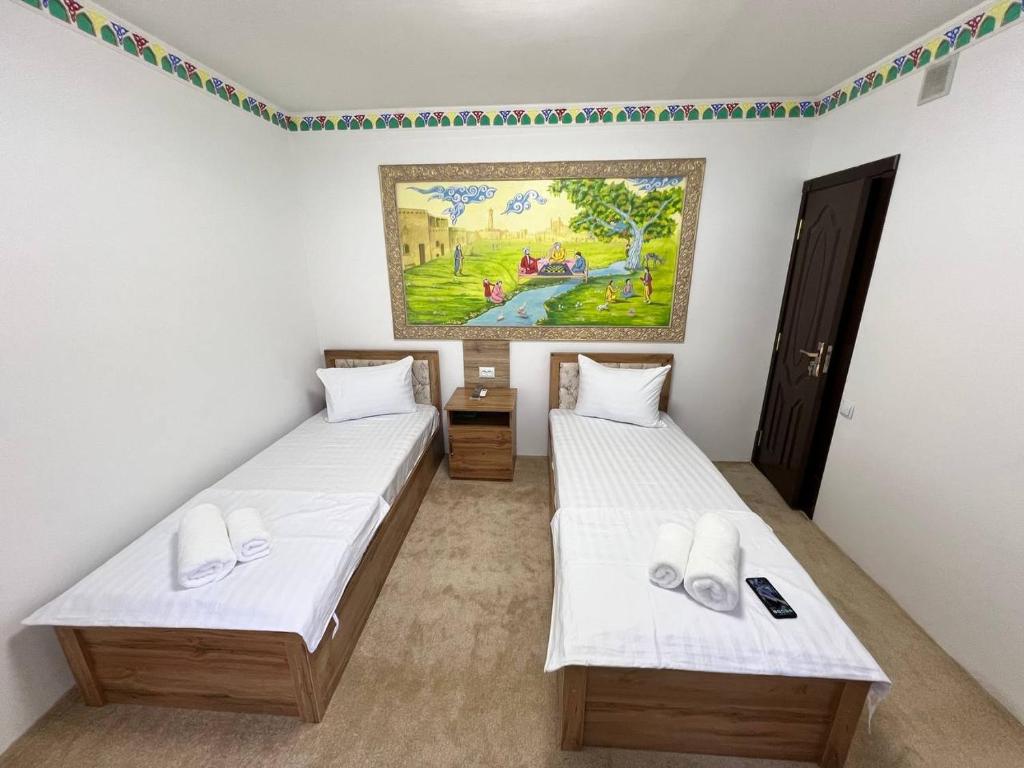 duas camas num quarto com um quadro na parede em Afsana Hotel em Bukhara