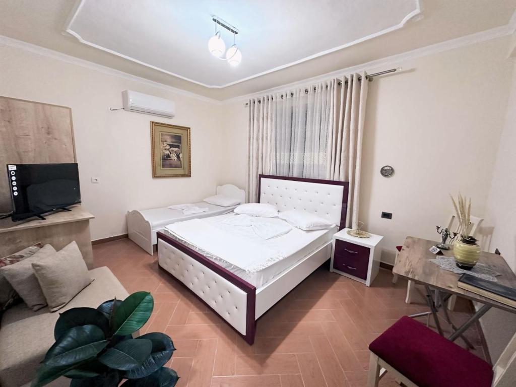 een slaapkamer met 2 bedden, een tv en een bank bij Aron’s House in Krujë