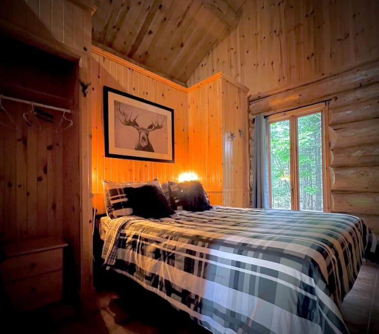 una camera con un letto in una baita di tronchi di Chalets Terre de L'Orme Chalet Bois Rond 2 a Saint-Gabriel-De-Valcartier