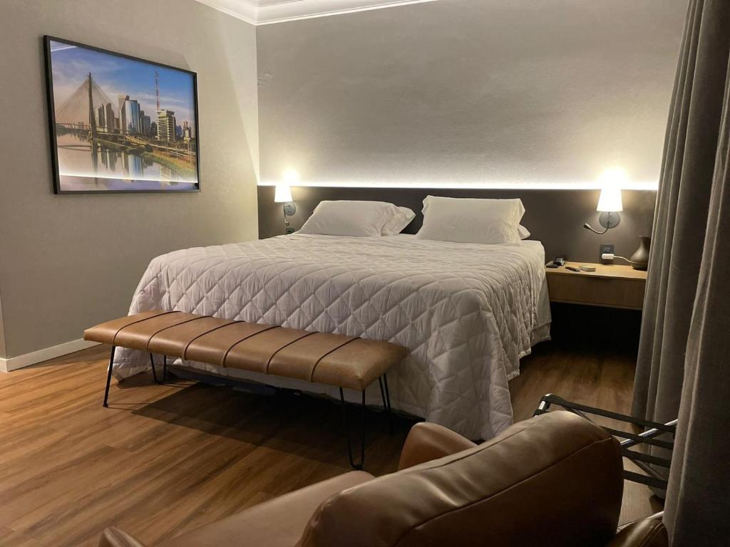 a hotel room with a bed and a chair at Flat Higienópolis Premium in Sao Paulo