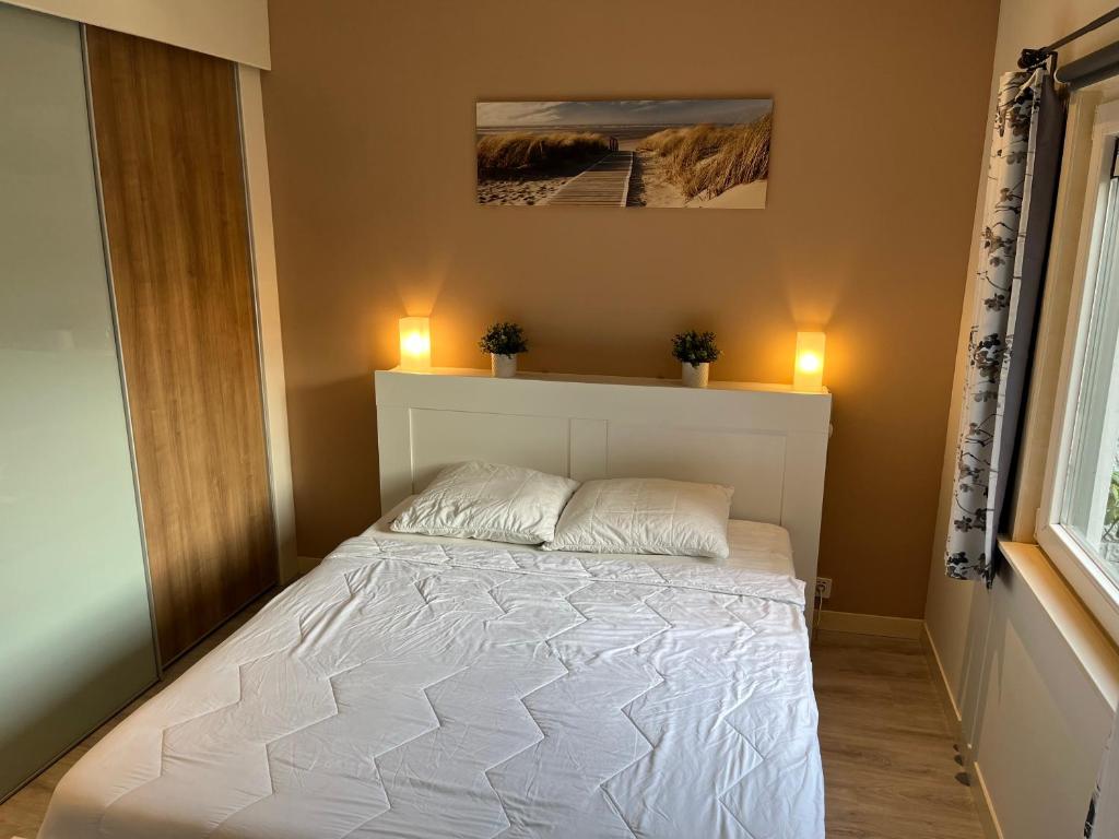 Un dormitorio con una cama blanca con dos luces. en Rustig gelegen recreatiewoning in Zeeland, en Bruinisse