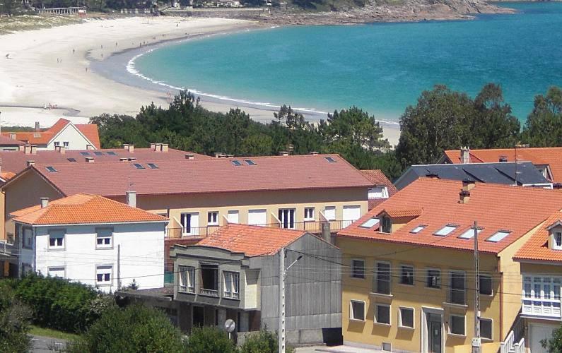 un groupe de maisons avec une plage en arrière-plan dans l'établissement Ático - Avenida Galicia 60, à Finisterre